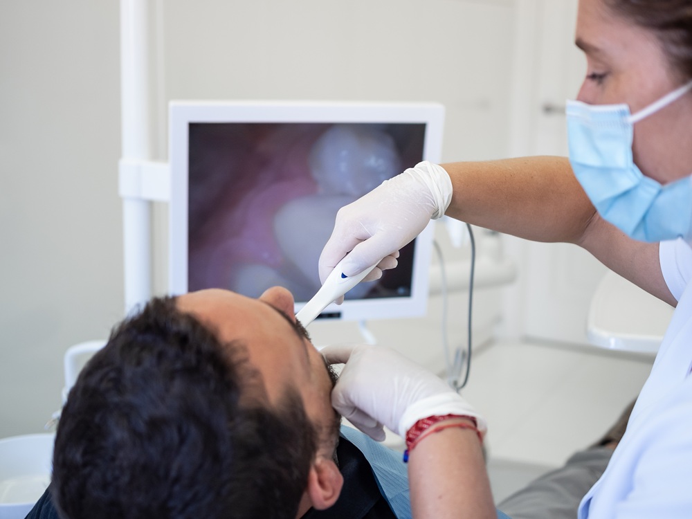A dentist performs a detailed oral exam using an intraoral camera, displaying magnified images of the patient’s teeth for improved care and documentation. – Intraoral Camera