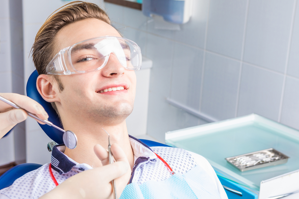 A smiling patient sits in the dental chair as the dentist prepares for a dental implant procedure designed to restore missing teeth and improve oral health. – Dental Implants