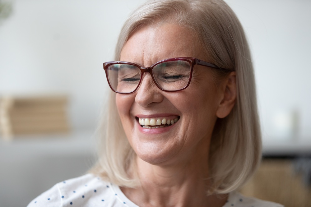A woman with glasses smiles joyfully, displaying the results of expertly crafted crowns or bridges that restore both beauty and confidence. – Crowns & Bridges