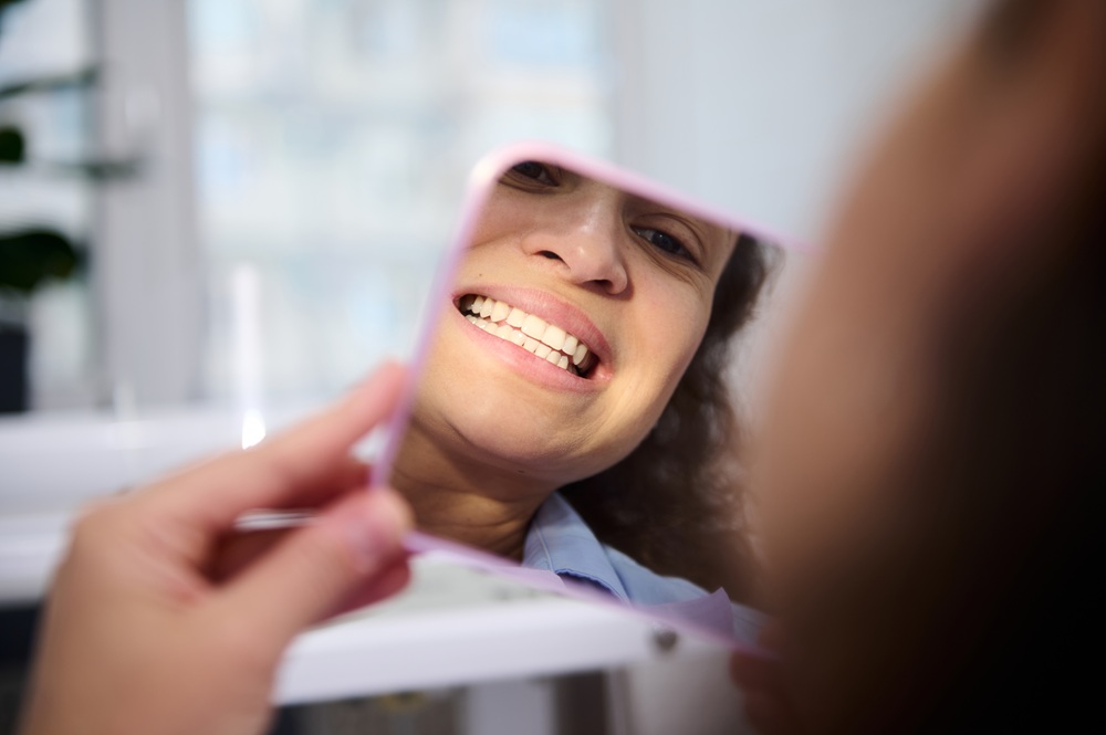A patient looks in the mirror, pleased with her newly restored tooth after a smooth and precise dental filling procedure. – Fillings