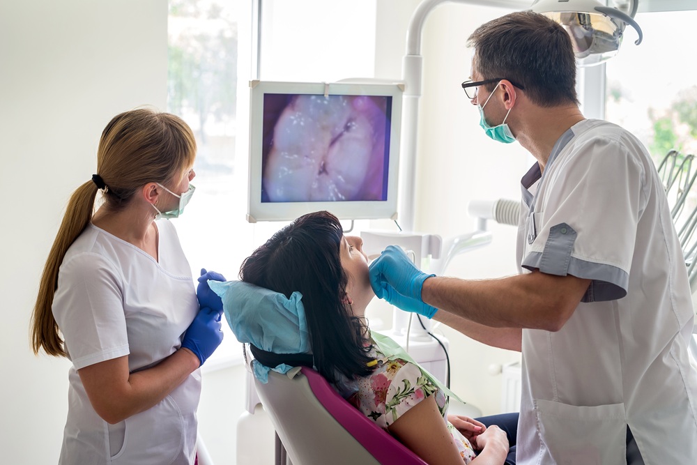 A dental team uses an intraoral camera to display real-time images of a patient’s mouth on a monitor, enhancing communication and treatment precision. – Intraoral Camera