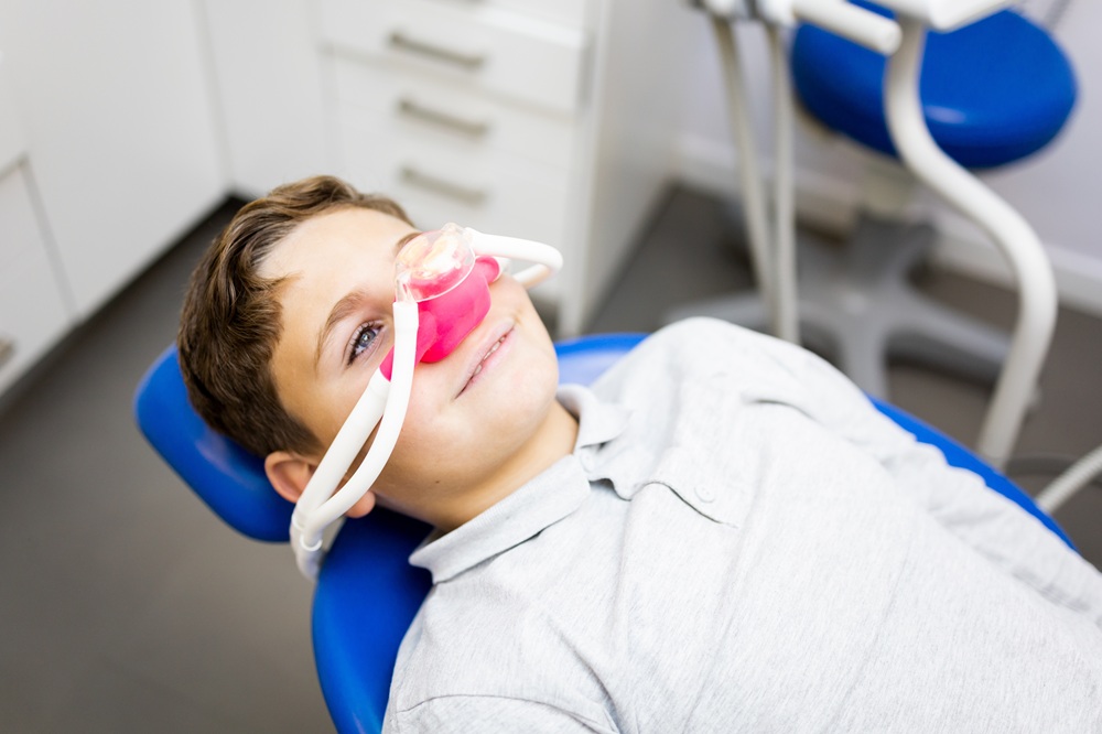 A young boy comfortably receives nitrous oxide sedation, allowing him to stay calm and relaxed during his dental treatment. – Sedation Dentistry