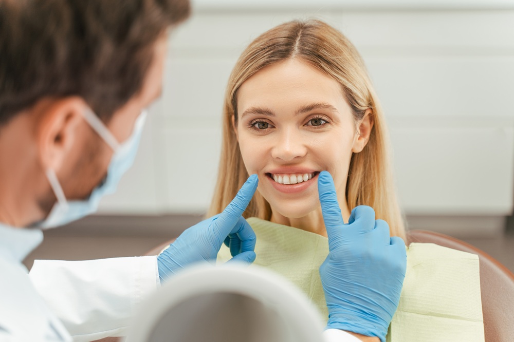 A dentist examines a patient’s bright smile after a cavity has been repaired with a natural-looking composite filling for seamless results. – Fillings