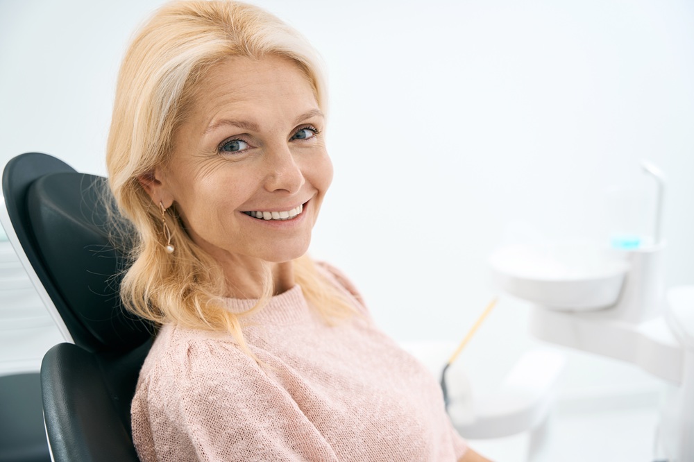 A mature woman smiles confidently after receiving dental crowns or bridges, showcasing restored function and a natural-looking smile. – Crowns & Bridges