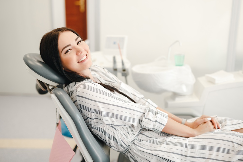 A smiling woman relaxes in the dental chair after receiving a tooth-colored filling, enjoying a comfortable and stress-free dental experience. – Fillings