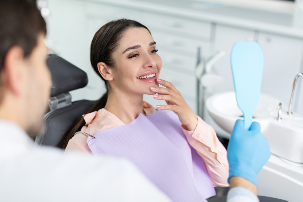 Patient Checking Smile After Dental Appointment – General Dentistry A woman admires her healthy, clean smile in the mirror after a routine dental visit focused on prevention and oral wellness. – General Dentistry
